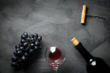 şarap cam, şişe, tirbuşon ve üzüm karanlık yüzeyi