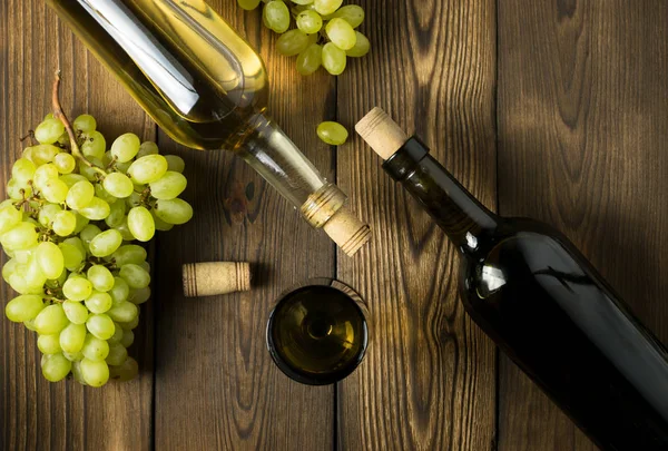 Ahşap masa arkasında mantarlı cam şarap şişesi.