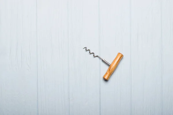 Corkscrew opener for wine cork on wooden background. Bottle-screw to open wine alcohol bottle at rustic vintage brown table.