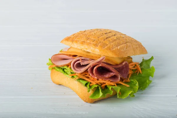 Pressed and toasted double panini with ham and cheese served on sandwich paper on a wooden table — Stock Photo, Image