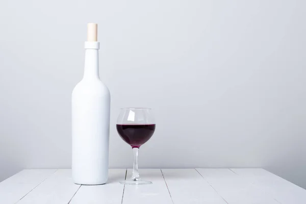 Garrafa de vinho tinto em um fundo de madeira branco — Fotografia de Stock