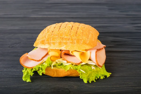 Pressed and toasted double panini with ham and cheese served on sandwich paper on a wooden table — Stock Photo, Image