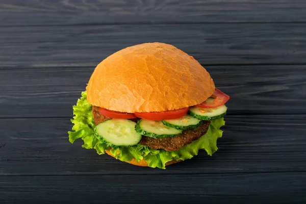 Craft burger de carne de vită pe masă de lemn izolată pe fundal albastru închis . — Fotografie, imagine de stoc