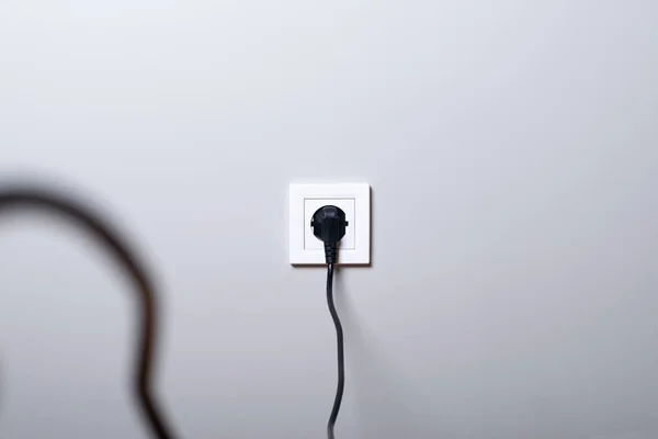 Elektrikli beyaz soket ve beyaz duvar arka plan üzerinde güç kablosu takılı bir — Stok fotoğraf
