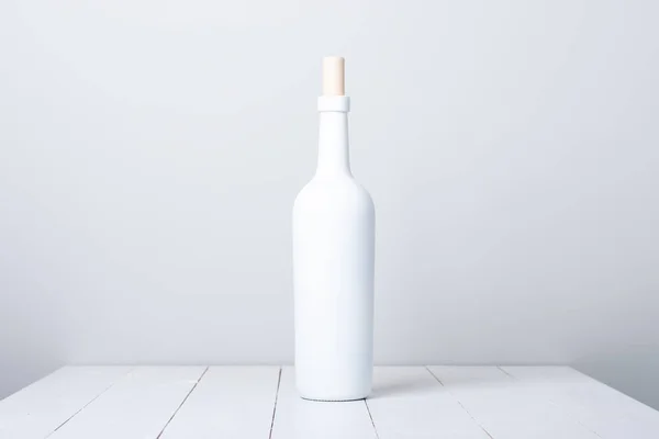 Garrafa de vinho tinto em um fundo de madeira branco — Fotografia de Stock