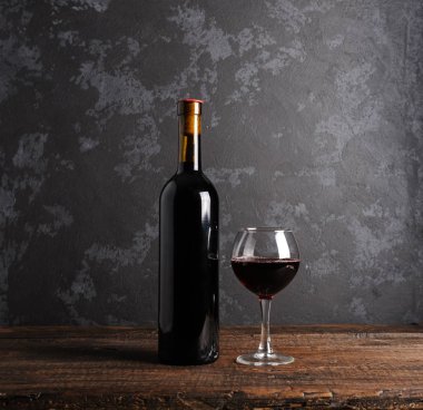 Ahşap arka planda kırmızı şarap şişesi.