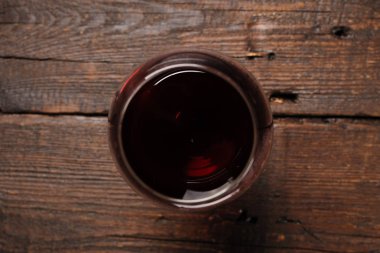 Ahşap masada bir kadeh kırmızı şarap. Yukarıdan görüntüle