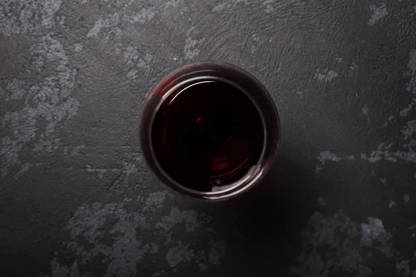 Koyu gri masada bir kadeh kırmızı şarap. Yukarıdan görüntüle