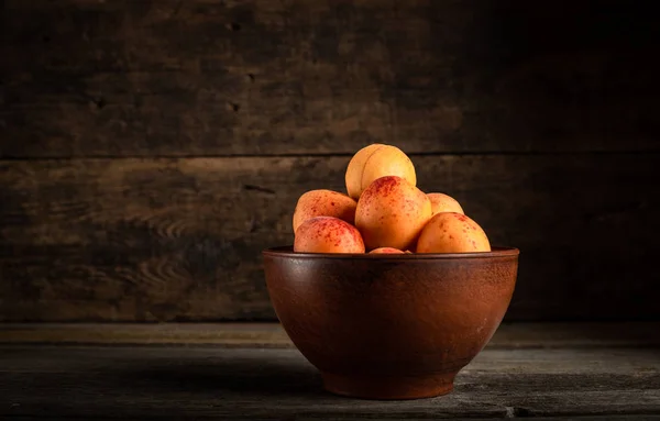 Tahta masadaki sepetin içinde taze kayısılar.
