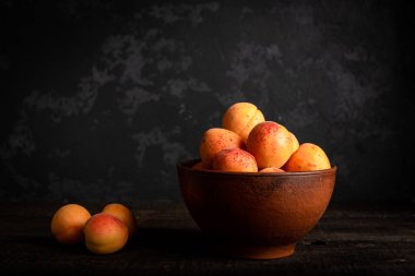 Tahta masadaki sepetin içinde taze kayısılar.