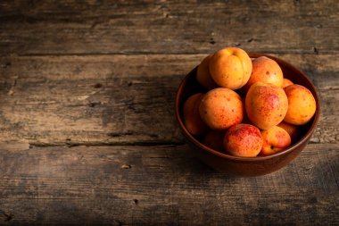 Tahta masadaki sepetin içinde taze kayısılar.