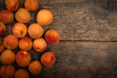 Masanın üzerindeki ahşap kasede lezzetli olgun kayısılar. Yukarıdan yatay görünüm