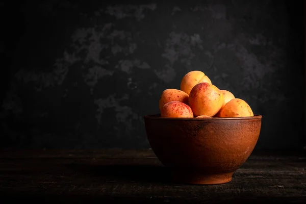 Tahta masadaki sepetin içinde taze kayısılar.