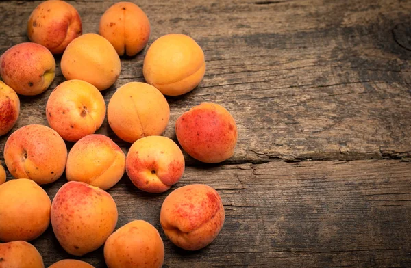 Masanın üzerindeki ahşap kasede lezzetli olgun kayısılar. Yukarıdan yatay görünüm