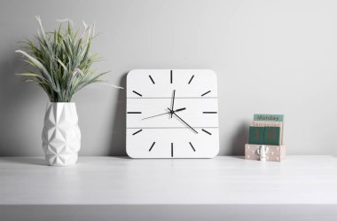 Iç. Ofis iç. Klasik çalar saat ve gri arka plan üzerinde potyeşil çim. İş iç ayrıntıları.