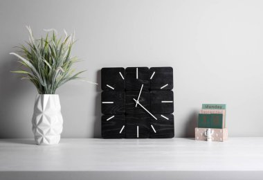 Iç. Ofis iç. Klasik çalar saat ve gri arka plan üzerinde potyeşil çim. İş iç ayrıntıları.