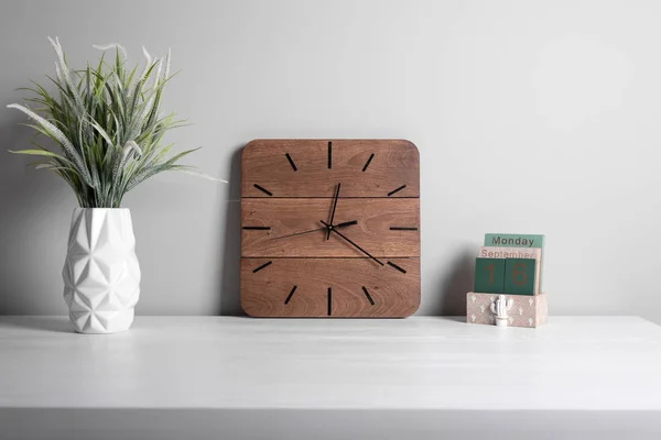 Iç. Ofis iç. Klasik çalar saat ve gri arka plan üzerinde potyeşil çim. İş iç ayrıntıları.