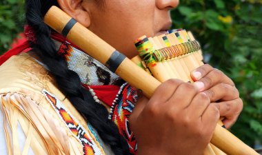 Native American plays music on wind instrument clipart