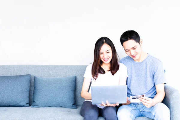 Happy young man and Beautiful pregnant sitting on couch with laptop computer. Happy Healthy Family Concept.