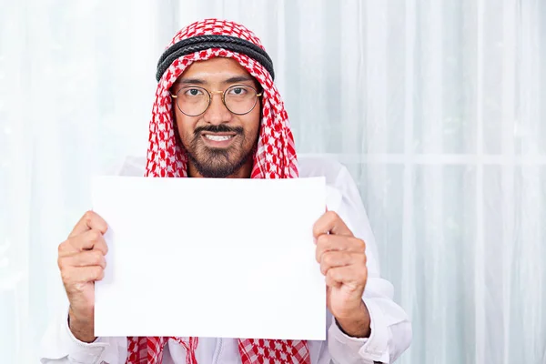 Happy Arab saudi man smiling and displaying a banner sign isolated on a white background.