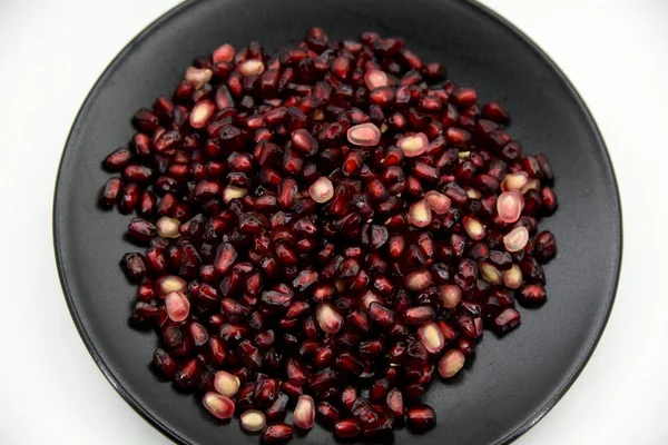 Pomegranate red grains on a black dish