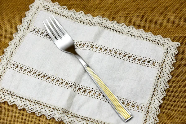 fork with golden features on lace napkin