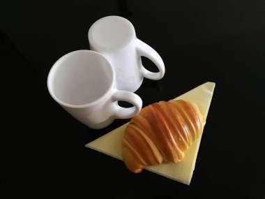 Kupası ve kruvasan siyah arka plan üzerine