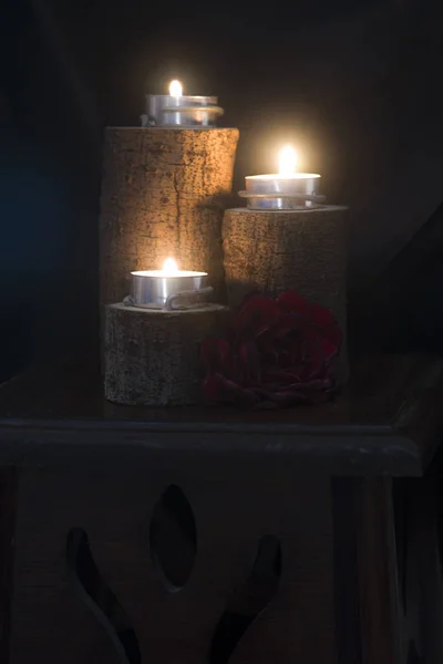 three candles lit in wooden candlesticks