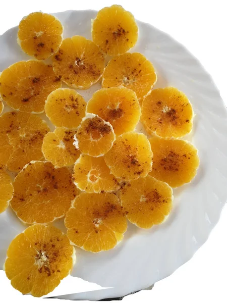 beyaz bir tabak üzerinde tarçın ile portakal slaytlar