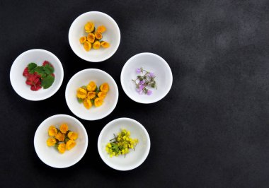 Gri arka plan üzerinde kır çiçekleri ile küçük kase