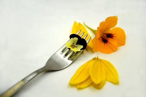 edible flowers and petals on white background and fork