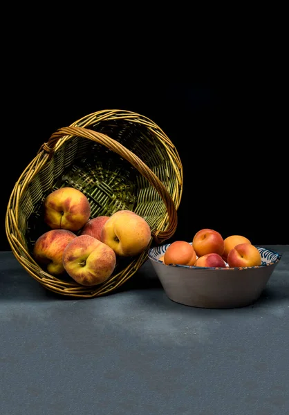 陶瓷盘上的杏仁和柳条筐上的桃子 图库图片