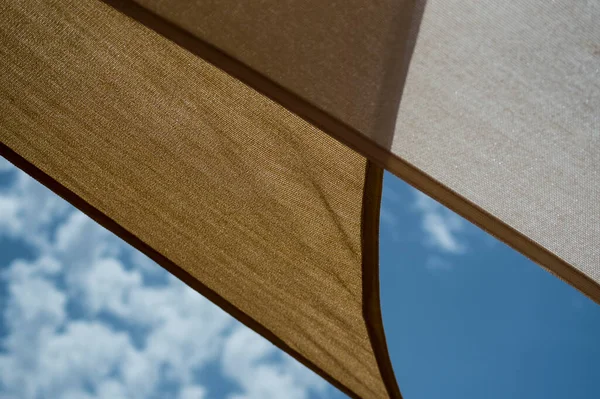 Bulutlu gökyüzünün altında üçgen tenteler