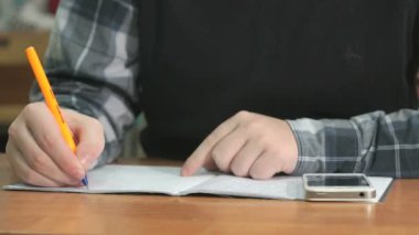 Bilinmeyen öğrenci defter kalem kullanarak metni yazar