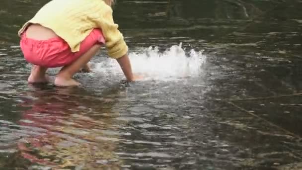 Little girl barefoot collects coins in fountain — Stock Video