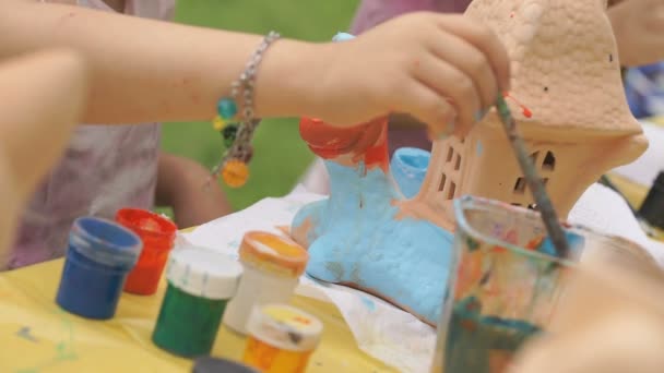 Dítě malířské štětce na hliněné postavu venku — Stock video