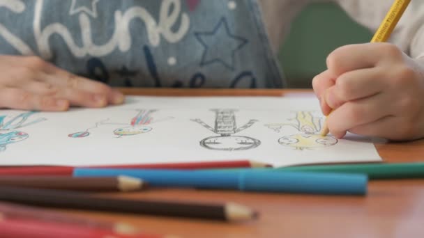 Маленькая девочка рисует картинки цветными карандашами — стоковое видео