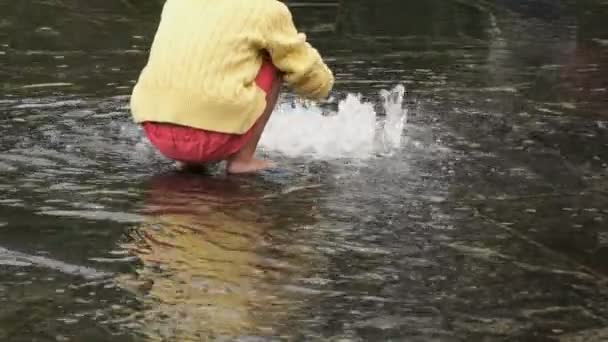 Маленькая девочка босиком собирает монеты в фонтане — стоковое видео
