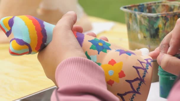 Child painting brushes on the clay figure outdoors — Stock Video