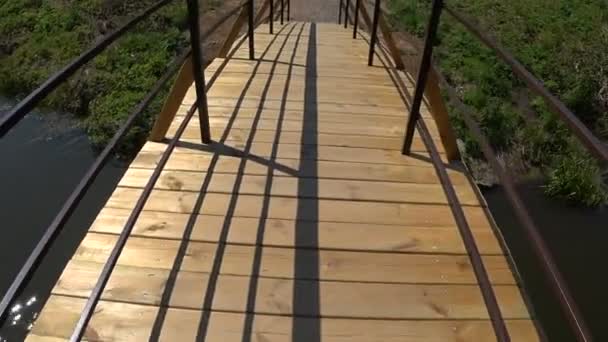 Cruzando ponte de madeira sobre o rio, ponto de vista . — Vídeo de Stock