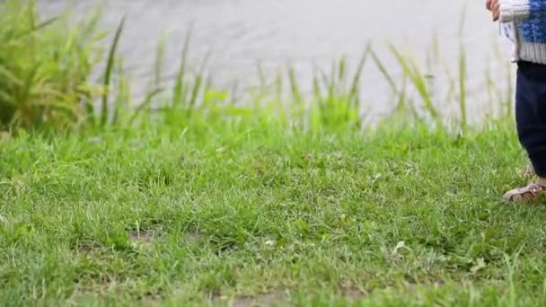 Il bambino va all'aperto, i primi passi del bambino, la mamma va dietro. Vista laterale, primo piano — Video Stock