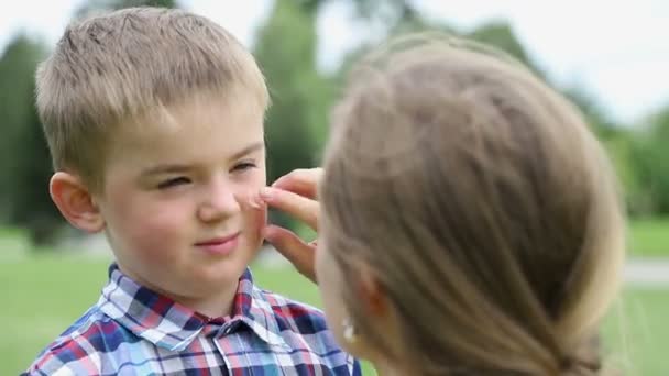 Een vrouw zet crème op een kind, close-up — Stockvideo