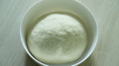 Hamur yükseliyor, zaman aşımı. Maya hamuru ahşap masada beyaz kase üzerinde yükselen. Pizza hamuru, khachapuri hamur