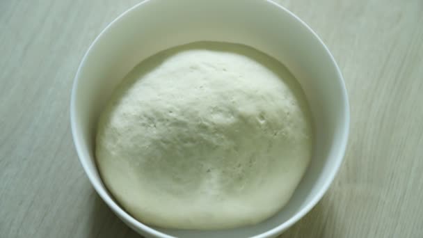 Dough rising, time lapse. Yeast dough rising on white bowl on wooden table. Pizza dough, khachapuri dough — Stock Video