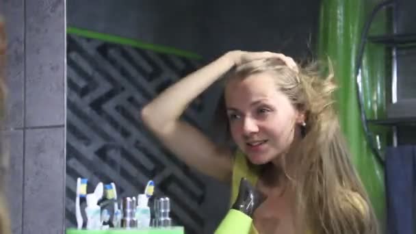 Genç güzel kadın aynaya bakar ve ıslak saç kurur ve banyoda şarkı — Stok video