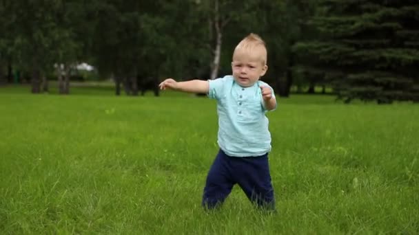 Bebeğin ilk adımları. Çocuk dengesini korumak için ellerini önünde tutar. — Stok video