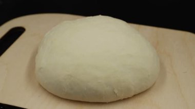 Zaman atlamalı. Maya hamurunun boyutu artar. Kesme tahtasındaki hamur siyah arka plan üzerinde yükselir.