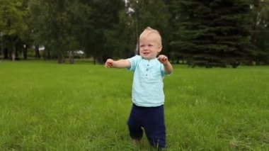 Bebeğin ilk adımları tam büyüme, açık havada. Beyaz etnik köken. Yavaş çekim