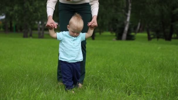 Перші кроки дитини хлопчика. Спочатку за допомогою матері, потім незалежних кроків . — стокове відео