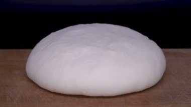 Maya hamuru zaman atlamalı yükselir. Siyah arka plan üzerinde kesme tahtası üzerinde Pasta.